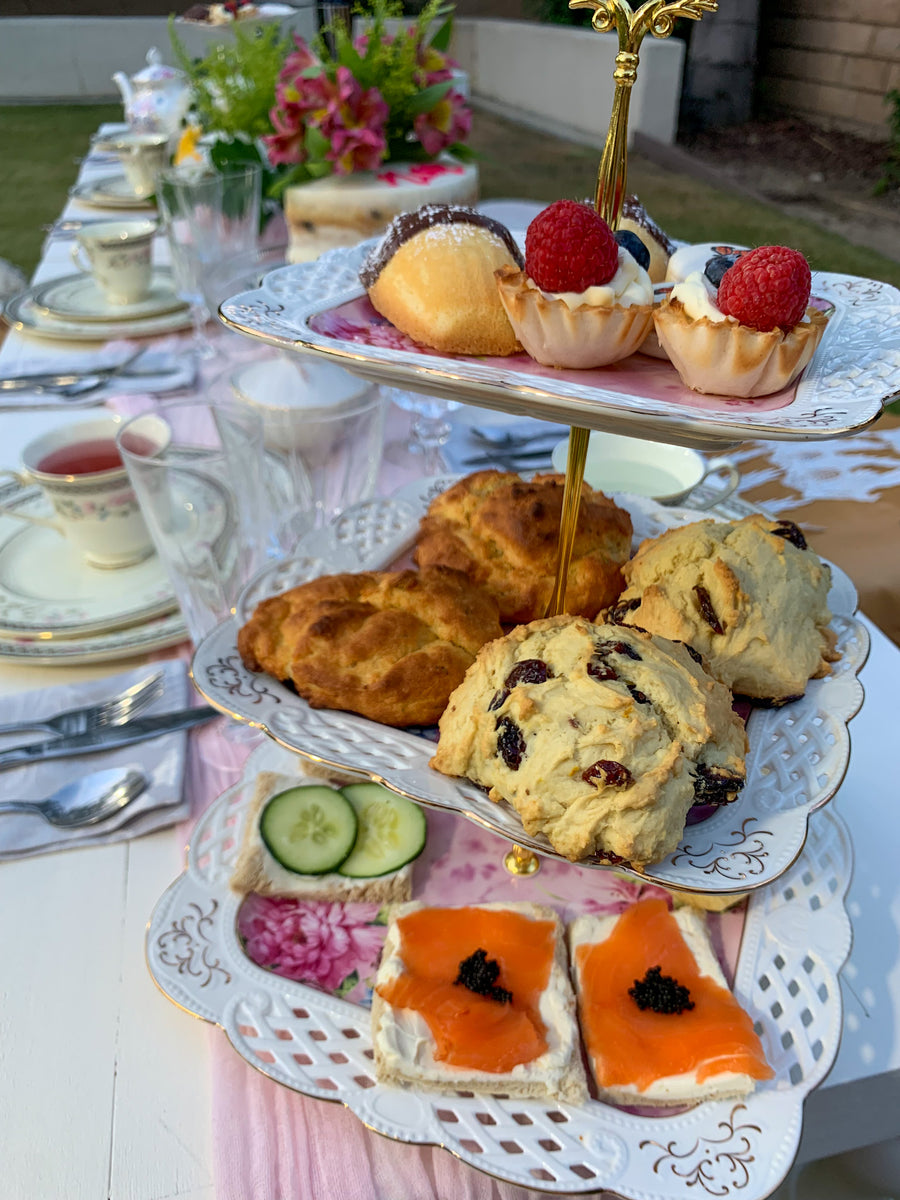 Tea plate tower with tea sandwiches and pastries on an outdoor picnic table