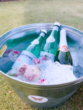 Load image into Gallery viewer, Beverage station with iced sparkling water and sparkling cider bottle in a large ice bucket outdoors
